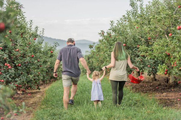 a family walking through an apple orchard