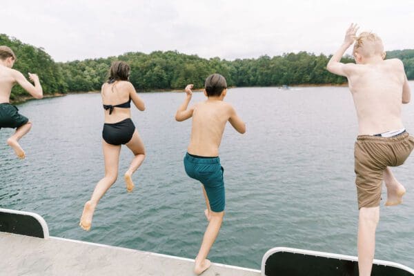 kids jumping off a boat into the lake