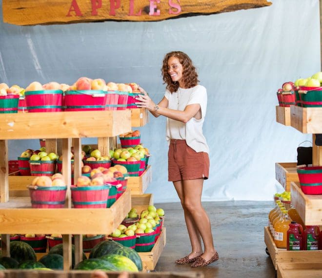 a woman browsing buckets of fresh peaches and apples