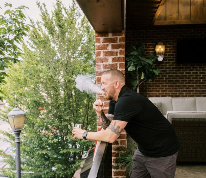 Man smoking a cigar outside on a patio