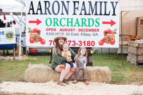 a mom and daughters sitting on hay bails