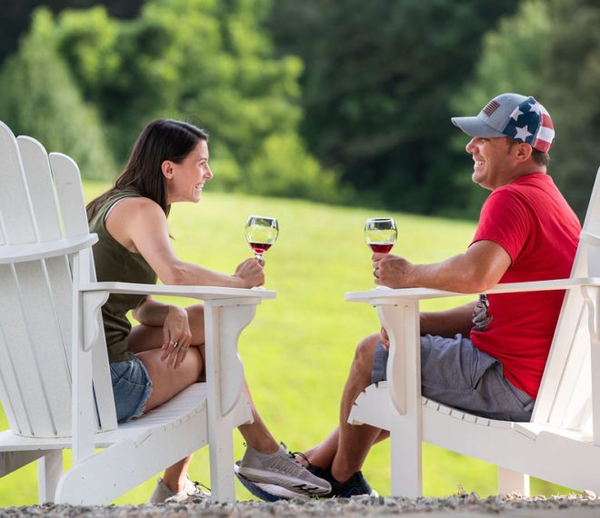 a couple enjoying wine outdoors in large Adirondack chairs