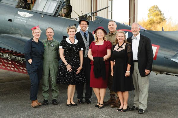 group of people dressed in old-time clothes next to an old war plane