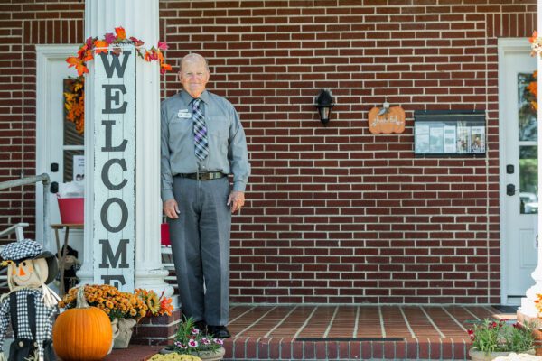 A man standing next to a fall welcome sign
