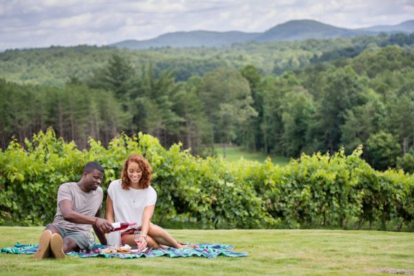 couple enjoying wine on a blanket in a beautiful field