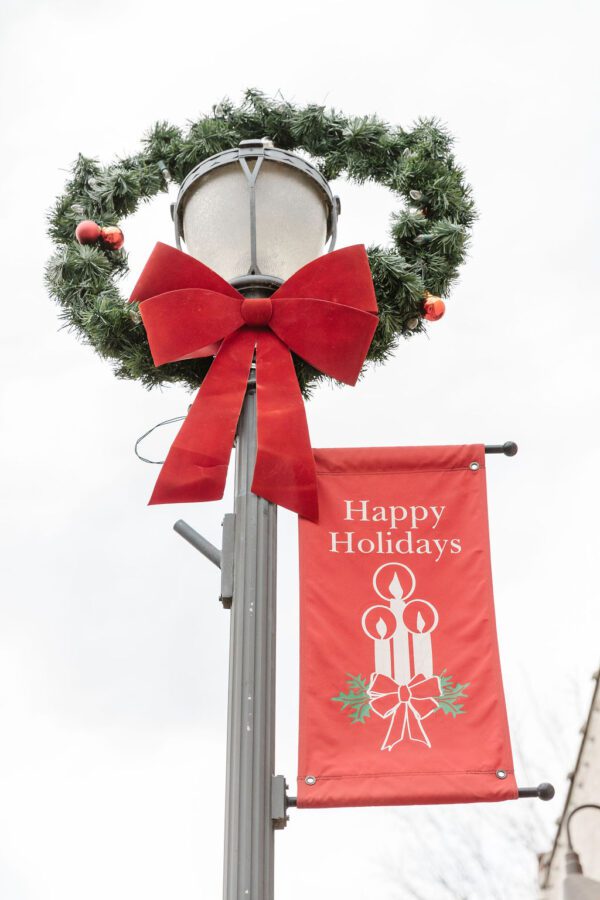 A wreath and Happy Holidays banner on a street lamp